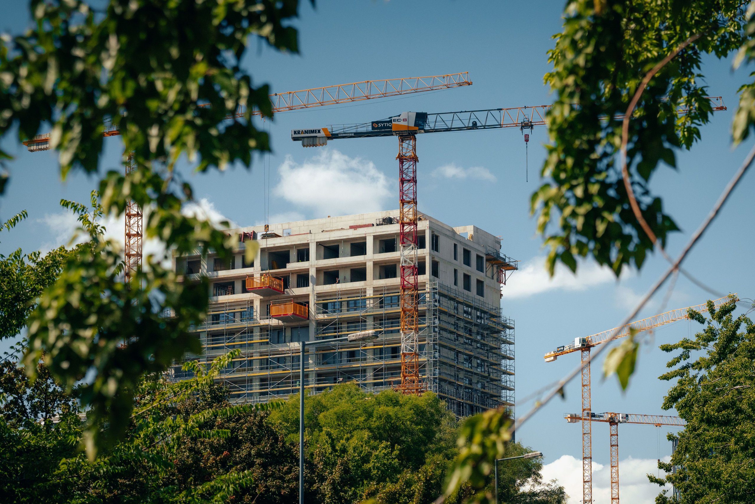 Condo tower under construction with cranes overhead